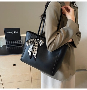 Detail of black PU leather tote bag with houndstooth ribbon worn by a model in a blazer