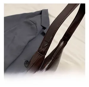Détail des coutures et du zip métallique sur le sac en cuir marron en demi-lune
