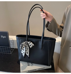 Close-up of black leather tote bag featuring a chic houndstooth silk scarf decoration