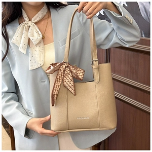 Detail of beige lychee pattern tote bag with decorative silk scarf and fashion logo