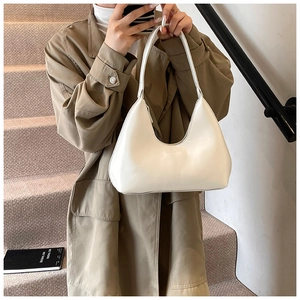 White minimalist crescent hobo bag shown over a khaki trench coat for a stylish daily commute