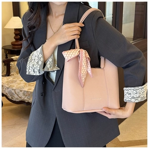 Detail of pink lychee leather bucket bag with elegant silk scarf on handle decoration