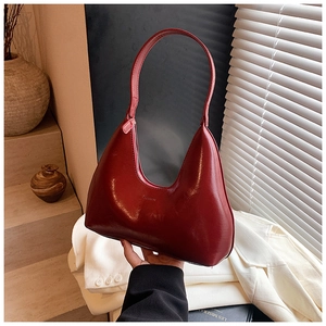 Detail of dark red crescent hobo bag with glossy leather texture and small fashion logo