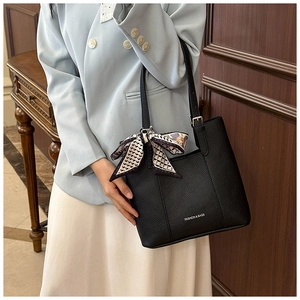 Detail of black lychee grain leather tote bag with decorative floral silk ribbon handle