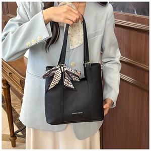 Detail of black pebbled leather tote bag with silk scarf charm and fashion lettering