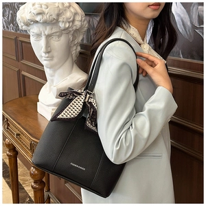 Close-up of black lychee leather bucket bag with fashion print and silk ribbon detail
