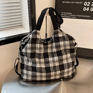Retro black and white checkered tote bag with wide strap on industrial background