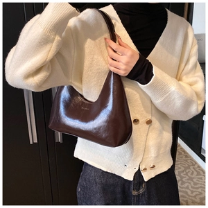 Detailed close-up of dark brown crescent bag in polished leather with fashion embossing