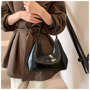 Détail du sac hobo noir brillant en cuir verni avec fermeture éclair métallique sur le haut