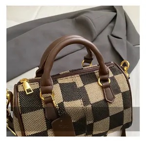 Detail of checkered houndstooth barrel bag with leather handles and gold metal zipper
