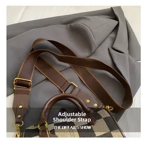 Detail of adjustable strap with gold metal hooks on a plaid canvas crossbody bag