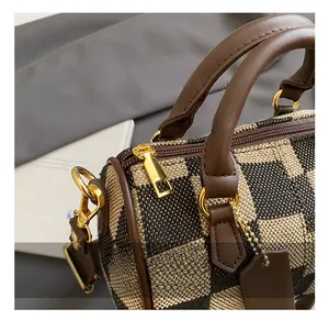 Detail showing golden hardware zippers and brown leather handles on checkerboard handbag