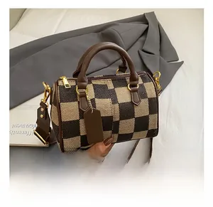 Detail showing checkered woven texture and brown leather handle on a stylish boston bag