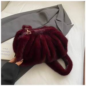 Close-up of plush burgundy faux fur handbag featuring elegant gold metal D-ring hardware