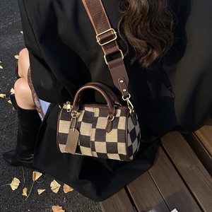 Detail of a vintage checkered crossbody bag with leather handles in an autumn outdoor setting
