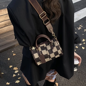 Detail of checkered Boston bag with leather trim and adjustable shoulder strap