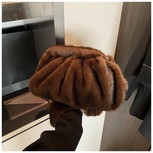 Detail of dark brown faux fur cloud clutch bag with soft texture and metallic zipper