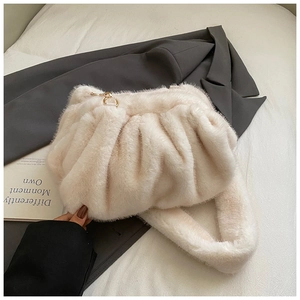 Detail of plush cream faux fur handbag with golden hardware on a stylish lifestyle background