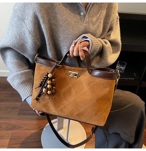 Detail of brown quilted suede tote bag with wooden bead tassel and gold turn-lock closure