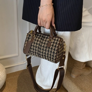 Close-up of vintage houndstooth Boston bag with leather handles and wide strap