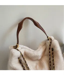Nahaufnahme der flauschigen cremeweißen Plüschtextur mit braunem Ledergriff und Kette