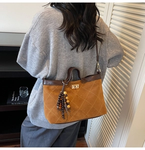 Detail of vintage brown quilted suede tote bag with leather trim and tassel charm