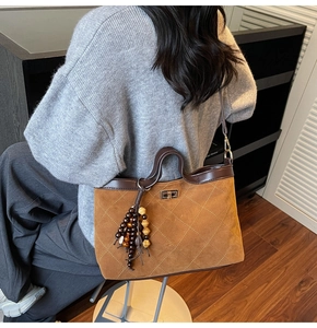 Detail of brown suede tote bag featuring quilted stitching and ethnic bead tassel decoration