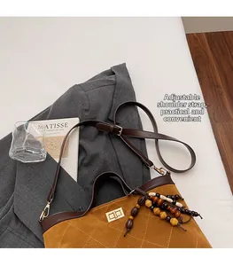 Detail of caramel suede tote bag with diamond quilting and adjustable leather strap
