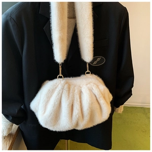 Detailed view of white faux fur cloud bag with plush strap on black suit background