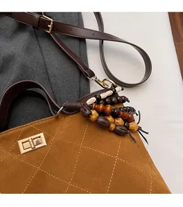 Detail view of caramel suede tote bag with diamond stitching and wooden bead tassel
