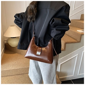 Detailweergave van de bruine lederen hobo-tas met zilveren gesp gedragen door model