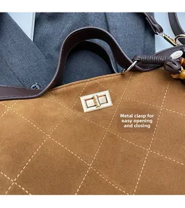 Detail of a brown suede tote bag featuring a golden twist-lock and quilted pattern