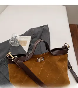 Detail of caramel quilted tote bag with golden metal lock and leather handles