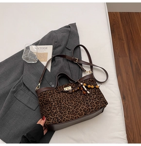 Detail of leopard print tote bag with metal twist lock and wooden bead charm on a blazer