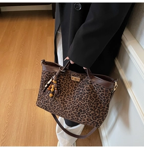 Detailed leopard print tote bag with brown leather trim and decorative beaded tassel charm