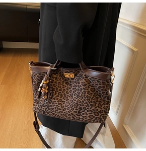 Detail of leopard print tote bag featuring wooden bead tassel and gold metal twist lock