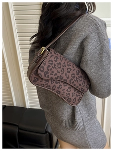 Detailed back view of a woman wearing a retro leopard print saddle bag under the arm