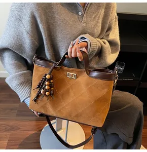 Detailed view of caramel quilted tote bag with brown leather handles and wood bead tassel