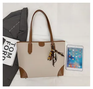 Detail of beige and brown leather tote bag with wooden bead tassel and contrast stitching