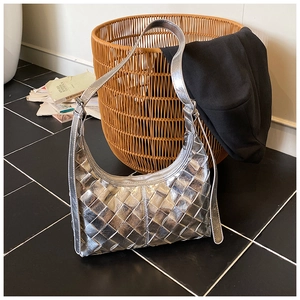 Detailansicht der silbernen geflochtenen Hobo-Tasche mit Metallic-Finish auf dunklem Boden