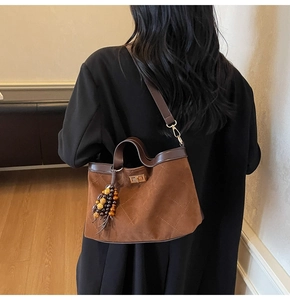 Detail of brown quilted suede tote bag with leather strap and decorative beaded tassel