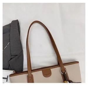 Detail of the stitching and leather logo plate on a beige and brown contrast tote bag