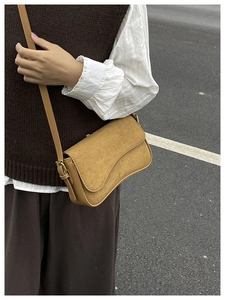 Detail of tan suede crossbody bag featuring gold metal buckle and vintage aesthetic