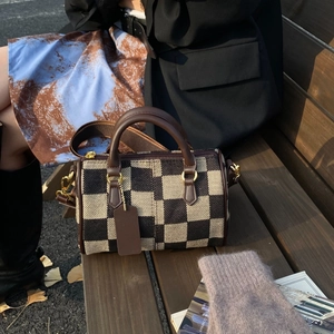 Classic checkered canvas boston handbag with brown leather trim on outdoor bench