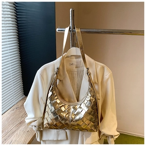Detail einer gold gewebten Hobo-Tasche mit großem Karomuster an einem weißen Blazer
