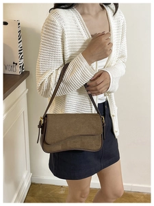 Detail of brown suede patchwork shoulder bag with gold hardware and curved flap design