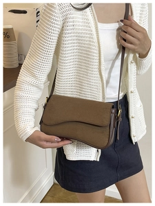 Detail view of the brown frosted suede texture and golden metal buckle on the shoulder bag