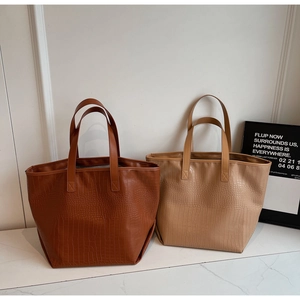 Detail showing high-quality crocodile texture on large tote bags in brown and khaki