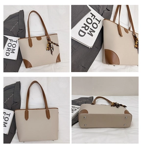 Detail view of large beige tote bag with brown trim and metal protective feet on the bottom
