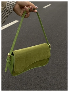 Macro detail of grass green leather underarm bag with gold metal buckle and suede texture
